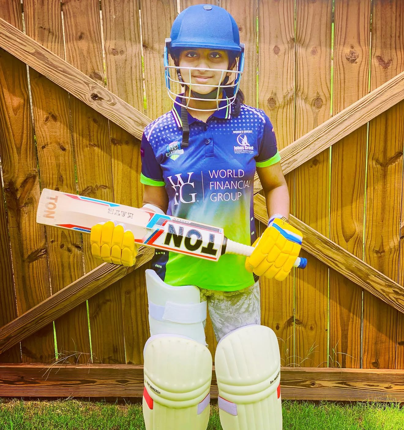 Kate in cricket gear with bat and pads
